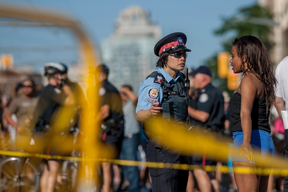 A member of the Toronto Police Auxiliary force speaks with a bystander after a man was stabbed in the chest and another cut during a fight at the Salsa on St. Clair festival on Saturday. The two day festival took place on St. Clair West between Winona and Christie. (July 13, 2013)