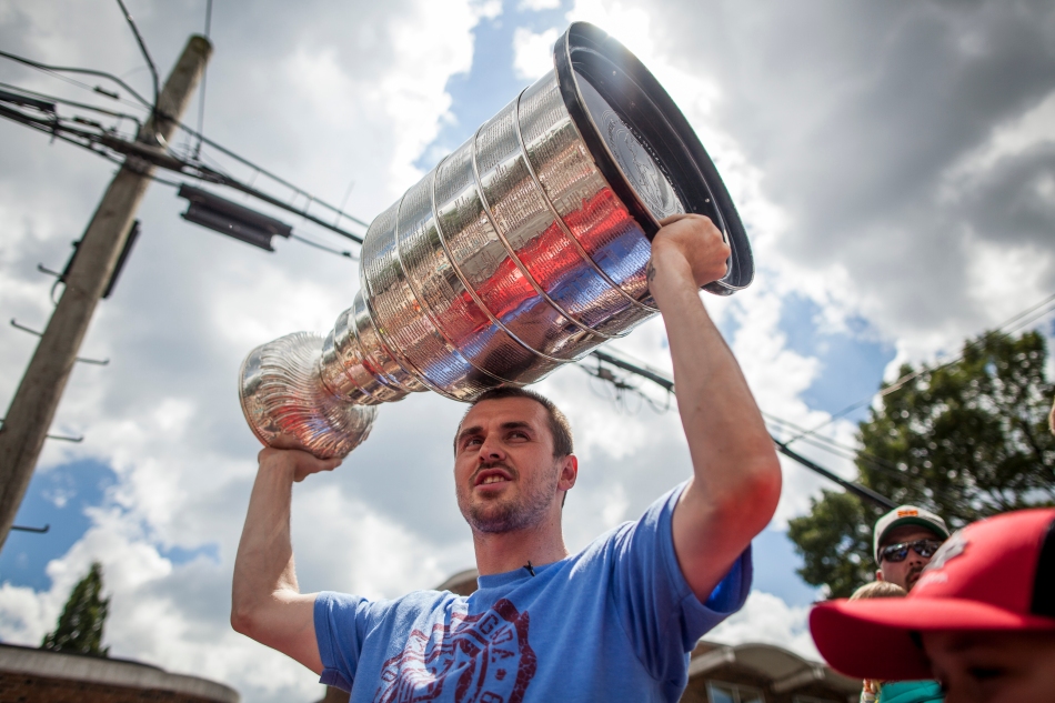 Former Chicago Blackhawk now Toronto Maple Leaf Dave Bolland holds the Stanley cup over his head during a parade down Mimico Avenue on Thursday. (August 1, 2013)