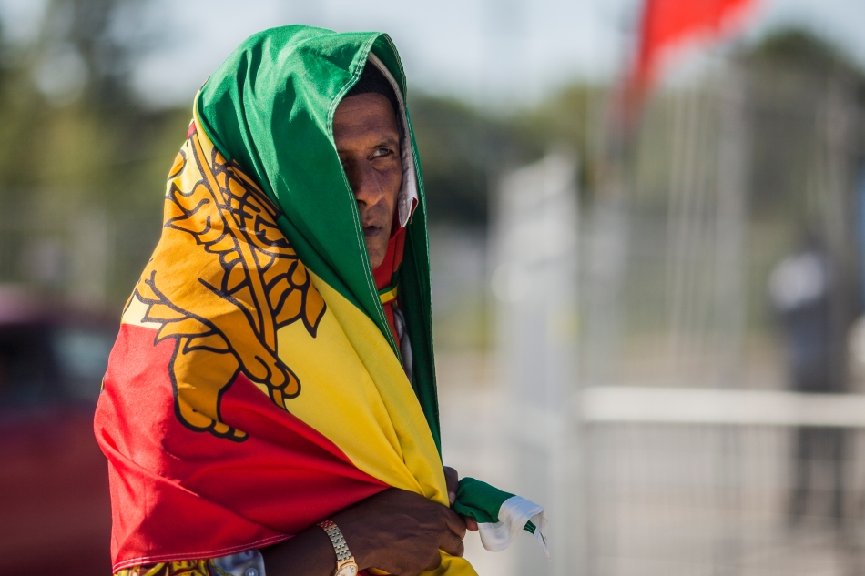 Adam Malaku waits for a performance to start while wrapped in a Rastafari flag on Saturday at the 2013 Rastafest at Downsview Park.  The flag is the same flag used by the state of Ethiopia 1897-1974. (August 24, 2013)