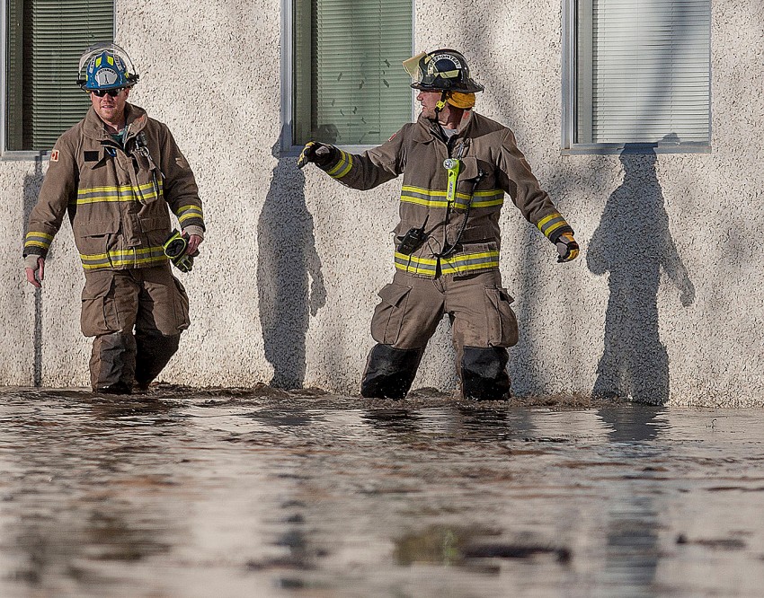 Firefighters walk along the outside of a building along 98 Street in downtown Peace River, Alberta after flooding occurred in areas around 98 Street and 100 Avenue on Tuesday April 8, 2014. According to authorities at the time the flooding seemed to be coming from a section of the Pat's Creek Culvert near that intersection. ADAM DIETRICH/RECORD-GAZETTE/QMI AGENCY