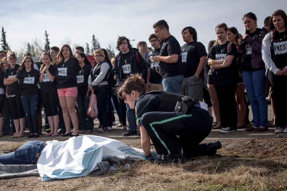 Layne Hankins, a junior firefighter from Nampa, plays dead while Peace River Alberta Health Services' Paramedic Tyne Lunn covers her with a blanket during a simulation of a fatal car accident for Peace River area high school students at the the St. Isidore fire hall on Wednesday May 21, 2014 In St Isidore Alberta. The simulation was part of the Preventing Alcohol and Risk Related Trauma in Youth (PARTY) program, which is designed to curb risky behaviour in youth by exposing them to the consequences through live dramatizations and presentations from law enforcement, paramedics, firefighters as well as victims and survivors. ADAM DIETRICH/RECORD-GAZETTE/QMI AGENCY